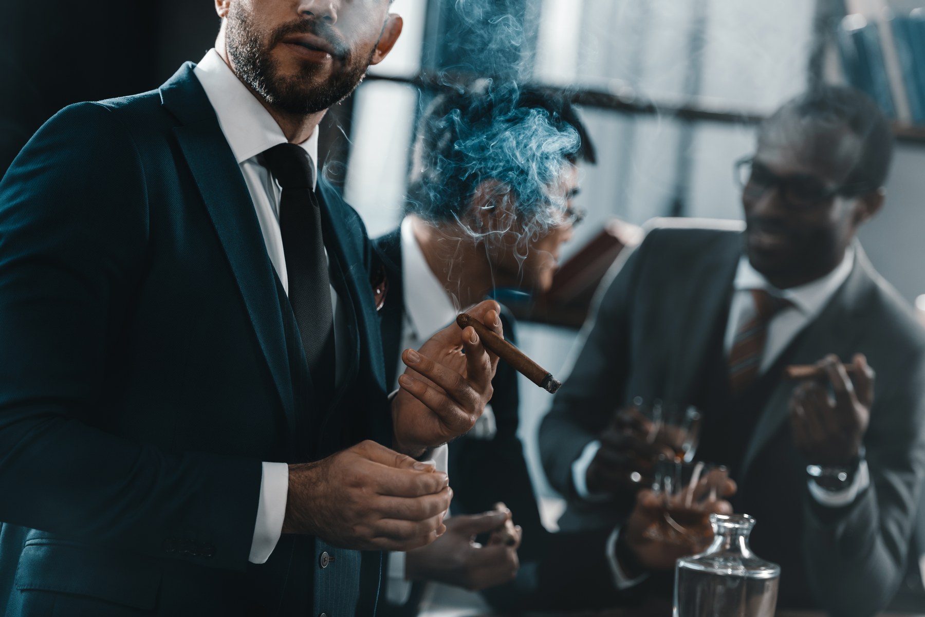 Guests in suits smoking cigars and drinking at an upscale event